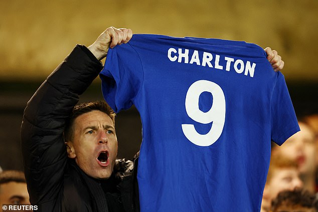 Manchester United fan displays a Bobby Charlton shirt in the stands before the match