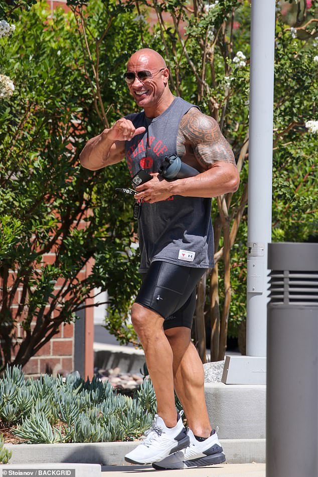 Hang loose: The actor and WWE icon sported a pair of aviator sunglasses and flashed a shaka ('hang loose') sign and a big smile while carrying his phone and a water bottle