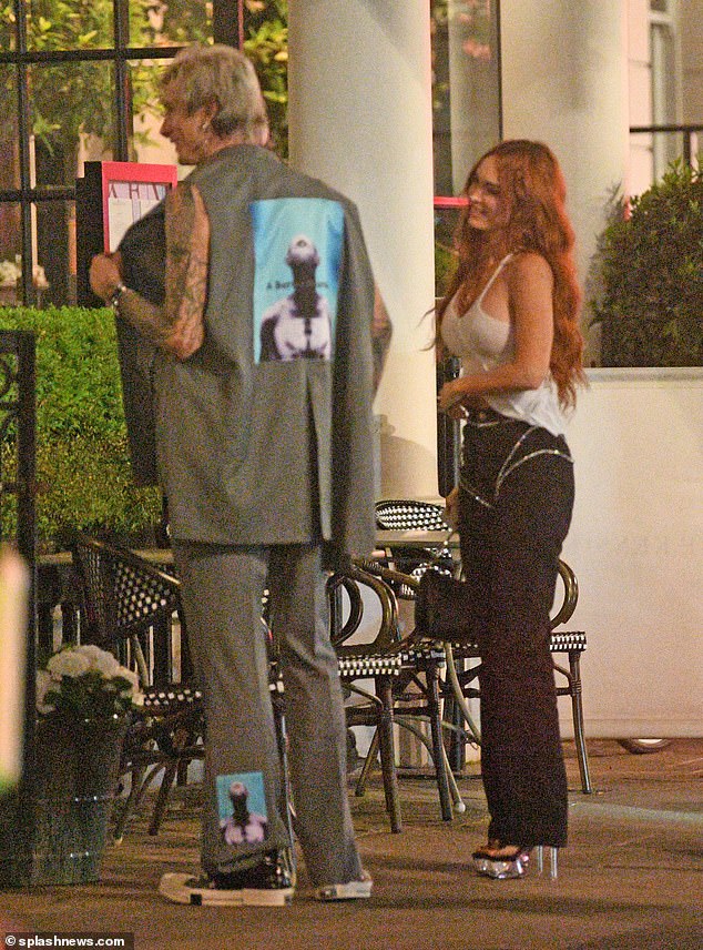 On the town: MGK also looked in good spirits as he chatted with a member of his entourage