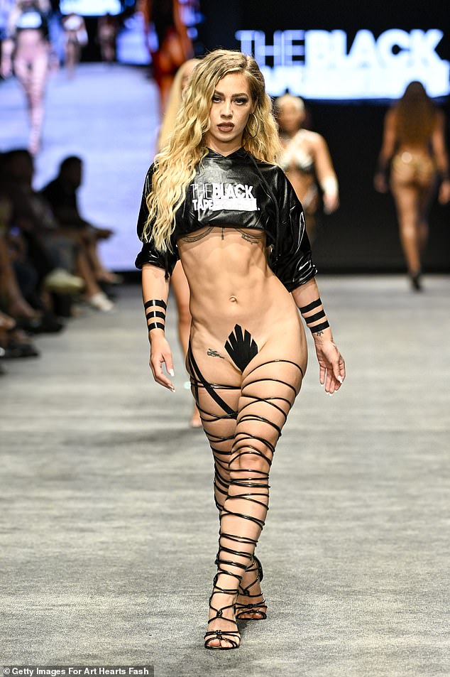 Miami Swim Week has been branded 'trashy' by industry insiders after outrageous 'duct tape bikini' trend leaving models to walk the runway almost naked divided the fashion world: 'It's almost comical'. Pictured is a model on the runway at the Black Tape Project show on July 7